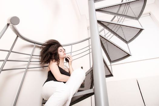 A young brazilian woman sitting on the stairs with a glass of red wine.