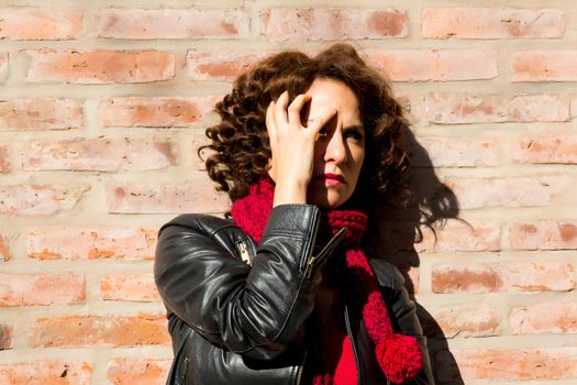 Worried woman standing at brick wall on the street.	
