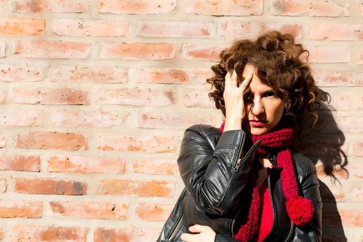 Worried woman standing at brick wall on the street.	
