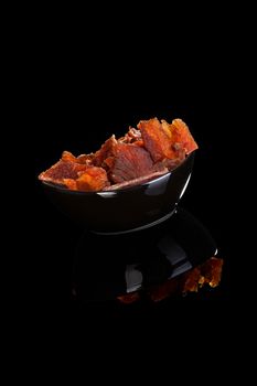 Beef jerky, dried meat in bowl isolated on black background. Culinary meat eating.