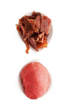 Beef jerky. Dry and fresh meat pieces in two bowls isolated on white background, top view. Delicious, culinary meat eating.