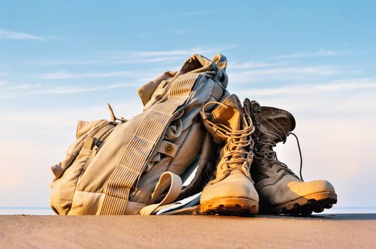 Yellow boots with a shoelaces and backpack on a sandy beach