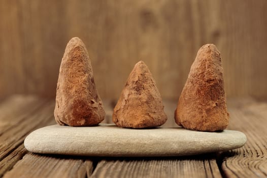 Homemade chocolate candies on stone on wood background