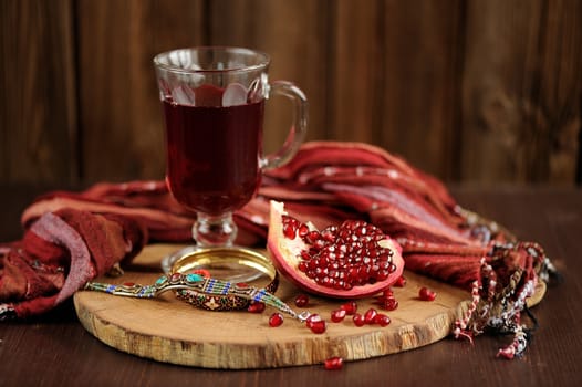 Peeled pomegranate, glass of pomegranate juice and jewerly on wooden board with wood background