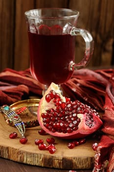 Peeled pomegranate, glass of pomegranate juice and jewerly on wooden board with wood background