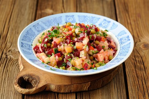 Russian beetroot salad vinegrette in blue plate on wooden background