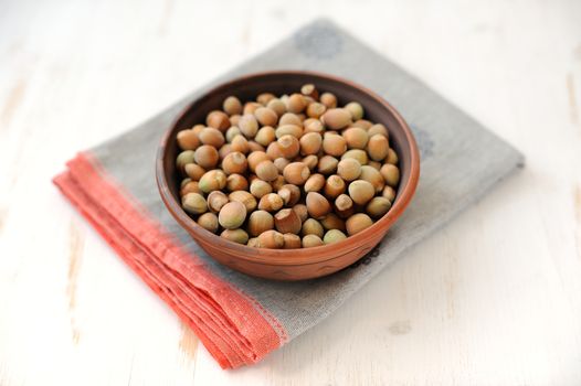 Hazel nuts in clay bowl on white table