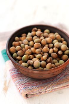 Hazel nuts in clay bowl on white table