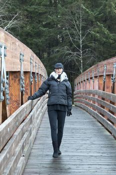 Asian senior woman in Juneau Alaska, on Fish Creek Trail, Douglas Island. Active senior bundled up in cold weather clothes for outdoor walking.  