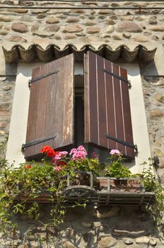 Vintage window with wooden shutters and pot flowers  in Borguetto, a charming village of Italy.