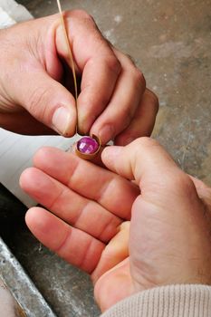 Skilled hands that create handmade jewelry with gold processing.