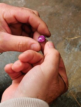 Skilled hands that create handmade jewelry with gold processing.