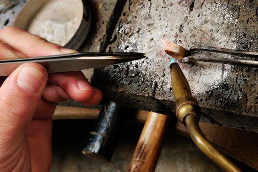 Skilled hands that create handmade jewelry with gold processing.