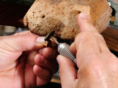 Skilled hands that create handmade jewelry with gold processing.