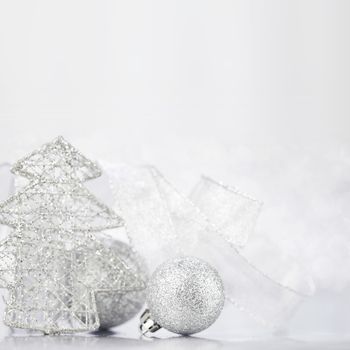 Christmas decorative fir and balls on light silver bokeh background