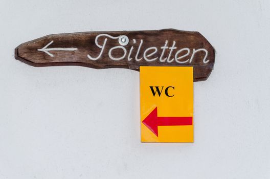 Wooden sign with inscription toilets with a small yellow sign toilet.