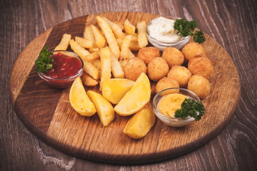 fried potato platter with dips  on wooden plate 