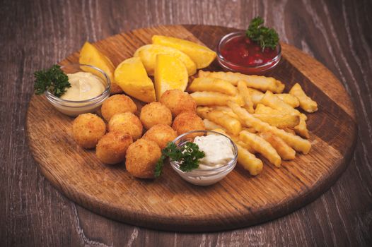 fried potato platter with dips  on wooden plate 