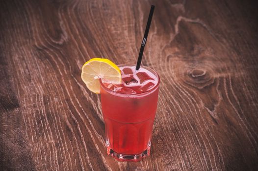 pink lemonade in glass with straw and lemon