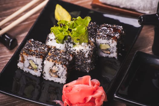 eel sushi roll with sesame seeds on black plate 