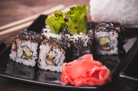 eel sushi roll with sesame seeds on black plate 