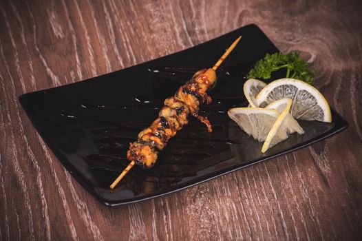 fried mussels skewer in sauce on black plate 