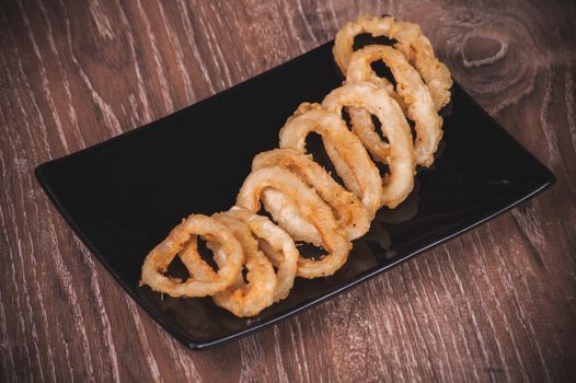 deep fried calamari squid rings on black plate 