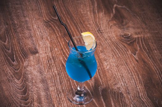 blue alcohol cocktail in high glass with straw 