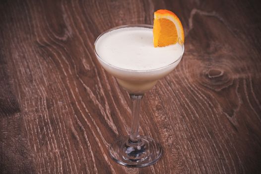 cocktail in high glass with orange in margarita glass