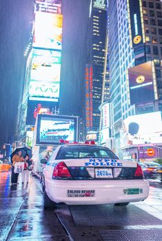 NEW YORK CITY - MAY 27: A wet Times Square May 27, 2013 in New York with tourists and police car. Times Square is the world's most visited tourist attraction bringing over 39 million tourists annually