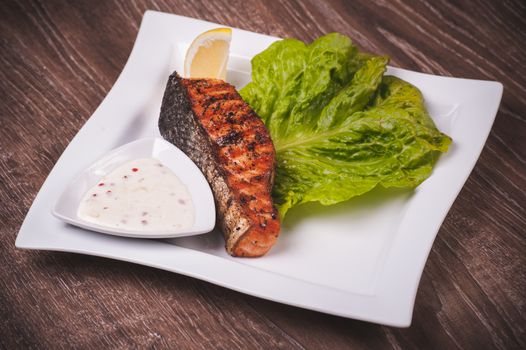 Grilled salmon with tartar sauce on white plate 