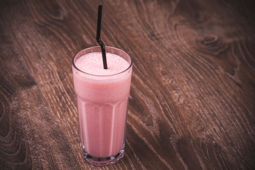 strawberry milkshake with straw in high glass