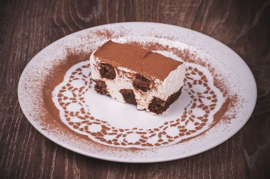 tiramisu dessert slice on white plate with cacao