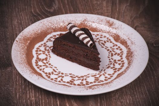 Chocolate cake slice on white plate with cacao 