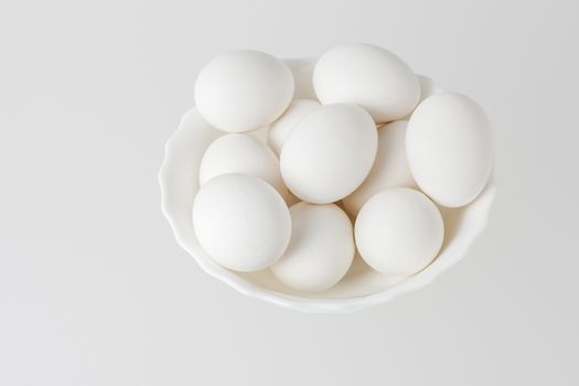 White eggs in a bowl on white background