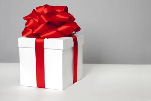 White gift box with red ribbon bow,