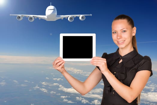 Beautiful businesswoman holding blank tablet PC. Blue sky, clowds and jet airliner as backdrop