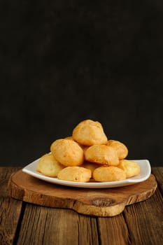 Gougeres on white plate on wooden background with space