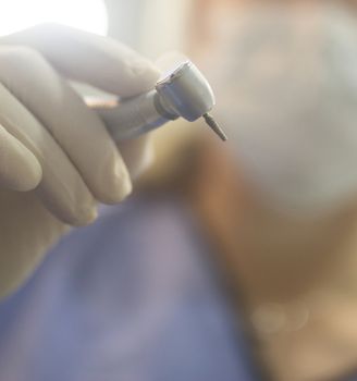 Dental instrumentation dentist pick tooth dental cleaning tool in the hand of dentist wearing face mask in dentists surgery clinic artistic color photo with shallow depth of focus.