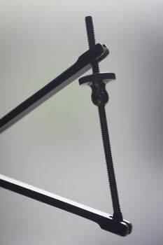 Traumatology orthopedic surgery instrumentation screw clamp in semi silhouette against plain studio background. 