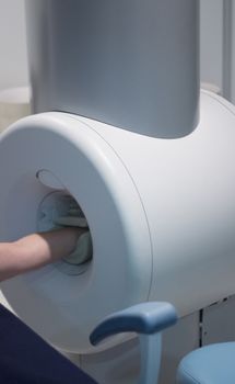 Completely open high field MRI scanner with patient lying with arm being scanned. Magnetic resonance imaging and scanning. 
