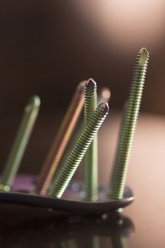 Traumatology orthopedic surgery implant titanium plate and green screws in semi silhouette against plain studio background. Close-up macro photograph in grey tones. 