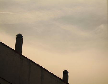 Metal chimney pots on roof of building and blue pink sky in Madrid Spain at dusk sunset diagonal shot.