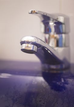 Domestic bathroom wash basin tap close-up photo with shallow depth of focus. 