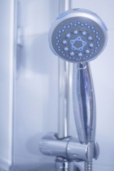 Domestic bathroom shower head and wall tiles close-up photo with shallow depth of focus. 