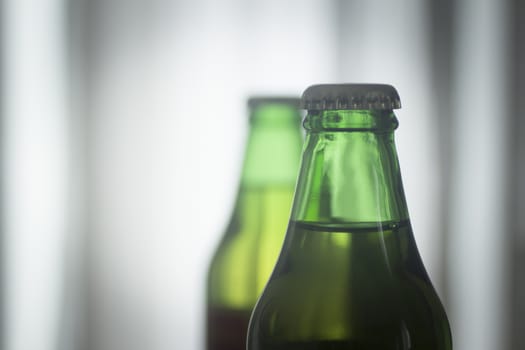 Isolated 200ml small glass Asturian Spanish apple cider bottles from Asturias Spain on a plain blue studio background close-up photo.