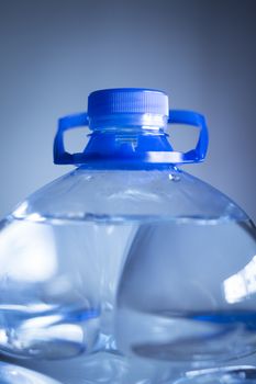 Isolated plastic water bottle on a plain blue studio background close-up photo. 