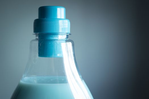 Bottle of washing liquid detergent fabric softener close-up product pack shot studio isolated on plain blue background with vignette effect. 