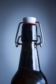 Lager beer bottle with clamp top studio isolated close-up on plain blue background color photo.