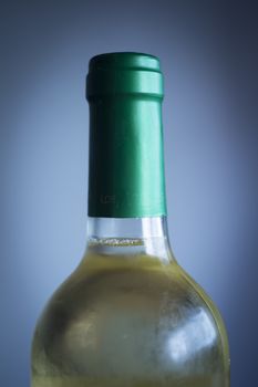 White wine bottle studio isolated close-up on plain blue background color photo.